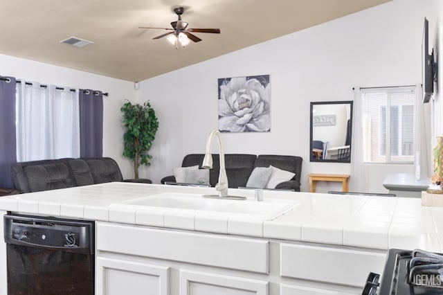 kitchen featuring lofted ceiling, tile counters, dishwasher, and white cabinets