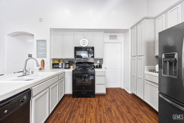 kitchen with tasteful backsplash, sink, dark wood-type flooring, and black appliances