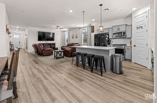 6607 Wind Wolfs Ln, Bakersfield, CA 93313 - kitchen featuring appliances with stainless steel finishes, gray cabinets, light wood-style flooring, a breakfast bar, and recessed lighting