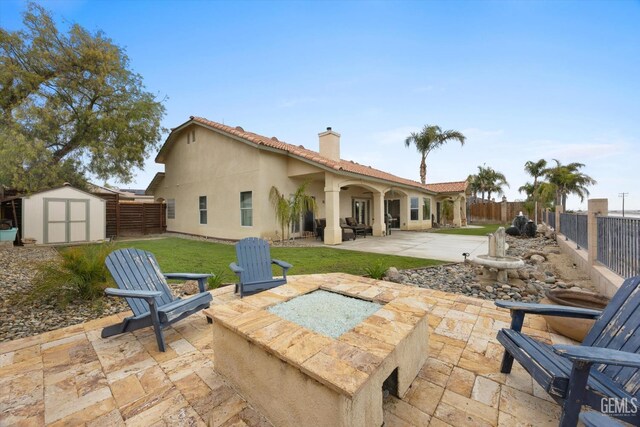 back of property featuring a chimney, a storage shed, a patio area, a fenced backyard, and stucco siding