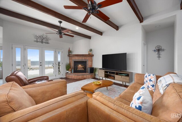 living room with a glass covered fireplace, beam ceiling, wood finished floors, ceiling fan, and french doors