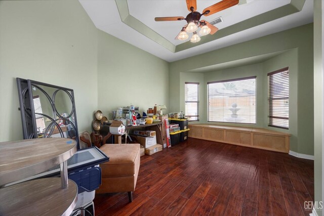 interior space with ceiling fan, visible vents, wood finished floors, and a raised ceiling