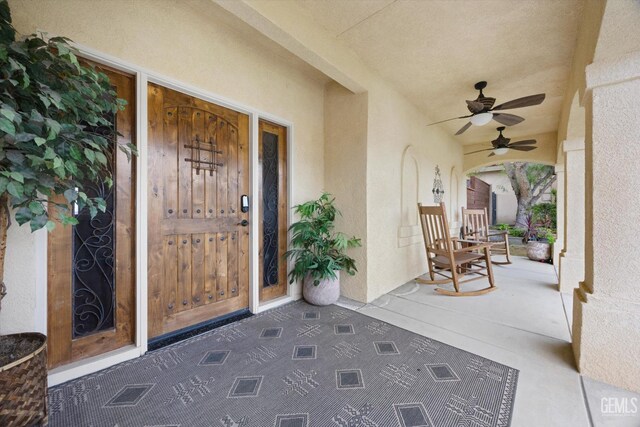 property entrance featuring covered porch, ceiling fan, and stucco siding
