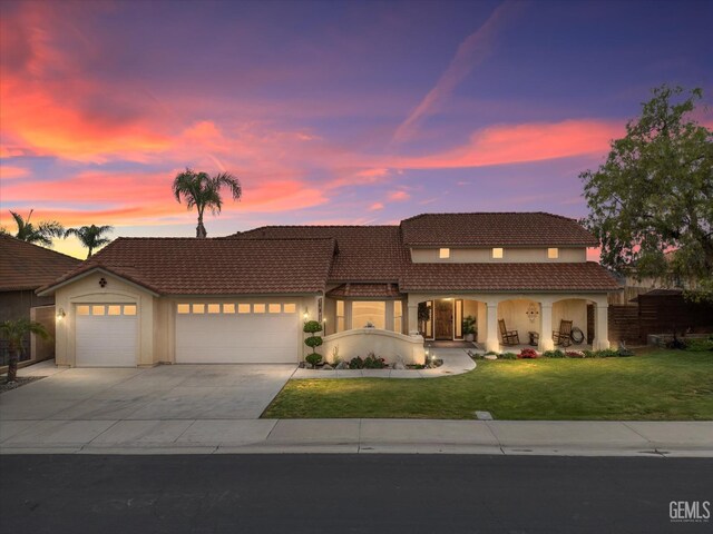 view of front of home featuring a front lawn, an attached garage, concrete driveway, and a tiled roof