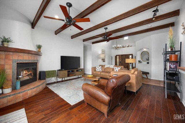 living area featuring beamed ceiling, ceiling fan with notable chandelier, a tile fireplace, and wood finished floors
