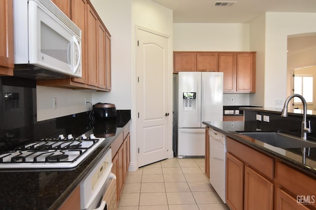 5712 Wisteria Valley Rd, Bakersfield, CA 93306 - kitchen with white appliances, a sink, brown cabinets, light tile patterned floors, and dark stone counters