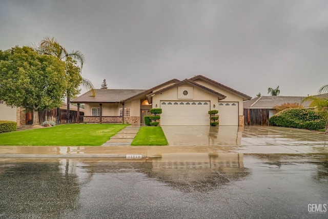 view of front facade featuring an attached garage, fence, concrete driveway, stucco siding, and a front yard