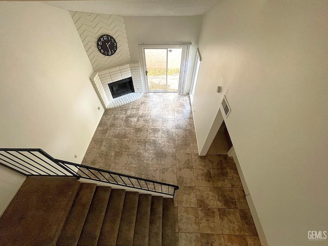 interior space featuring a brick fireplace, visible vents, stairway, and baseboards