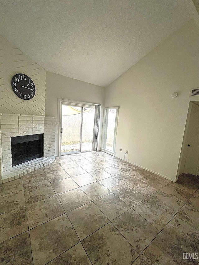 unfurnished living room with lofted ceiling, a brick fireplace, visible vents, and baseboards