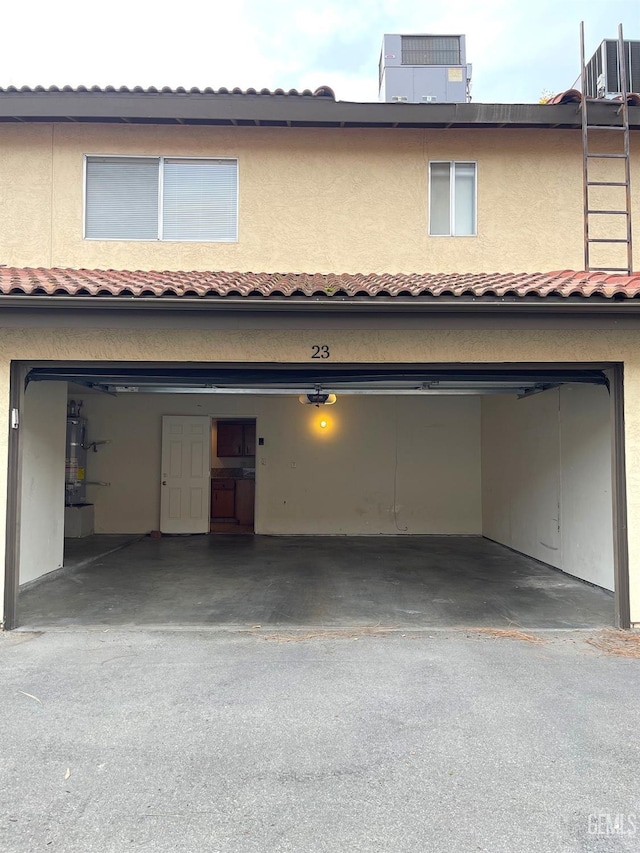 exterior space with a tile roof, stucco siding, water heater, central AC unit, and a garage