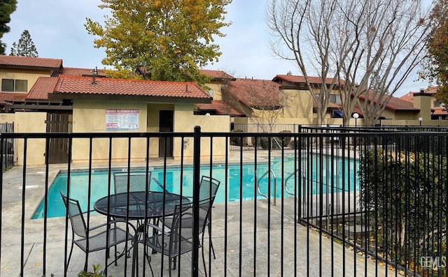 community pool with a patio area and fence