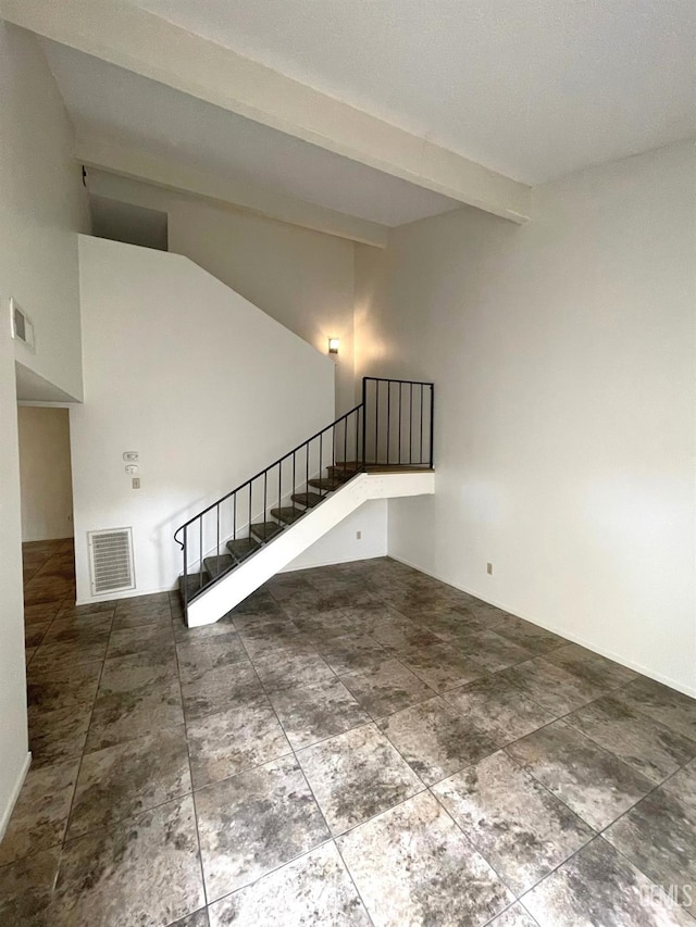 unfurnished living room featuring lofted ceiling with beams, stairway, and visible vents