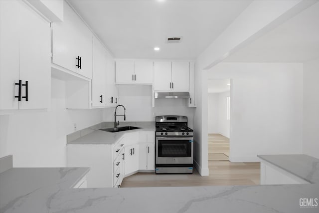 164 Rodriguez Ave, Shafter, CA 93263 - kitchen featuring gas stove, under cabinet range hood, light stone countertops, light wood-style floors, and white cabinetry