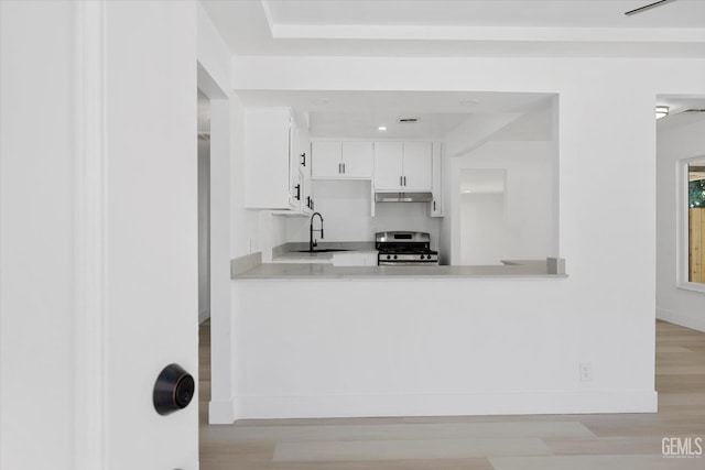 164 Rodriguez Ave, Shafter, CA 93263 - kitchen featuring gas stove, under cabinet range hood, light countertops, light wood-type flooring, and white cabinets