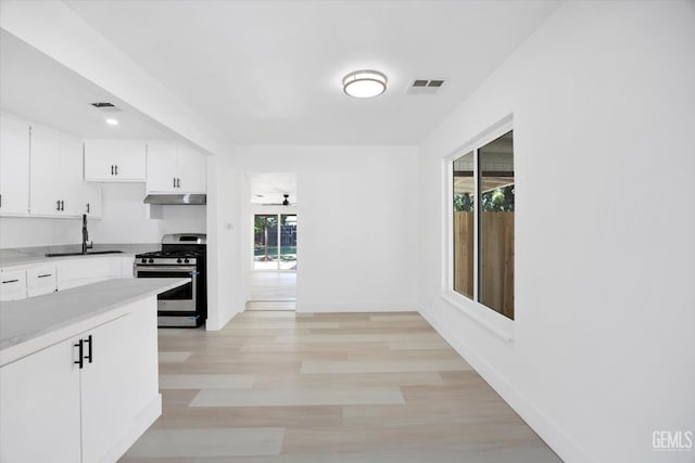 164 Rodriguez Ave, Shafter, CA 93263 - kitchen with stainless steel gas range oven, under cabinet range hood, white cabinetry, light wood-type flooring, and light countertops