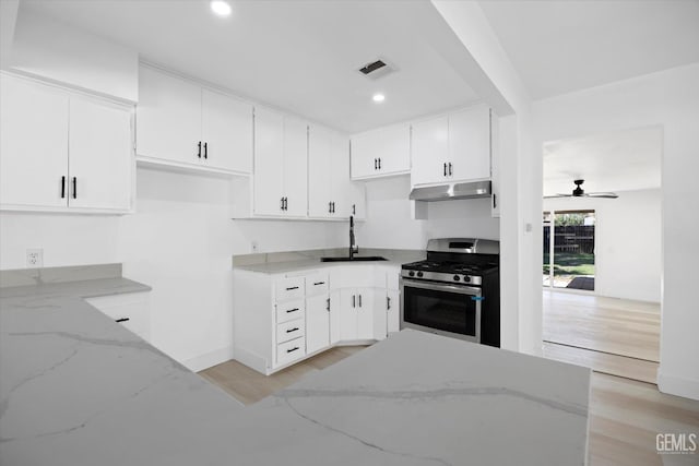 164 Rodriguez Ave, Shafter, CA 93263 - kitchen with stainless steel range with gas stovetop, under cabinet range hood, light stone countertops, light wood finished floors, and white cabinetry