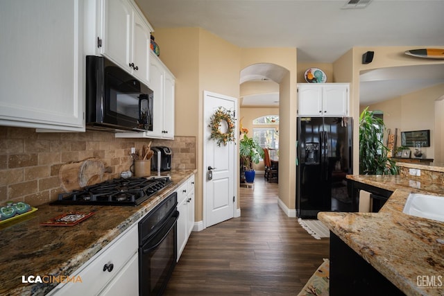 kitchen with tasteful backsplash, black appliances, dark hardwood / wood-style floors, light stone countertops, and white cabinets