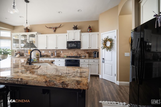 kitchen featuring dark hardwood / wood-style floors, white cabinetry, sink, backsplash, and black appliances