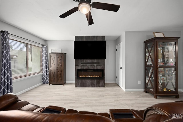 living room with a tiled fireplace, wood finished floors, and baseboards