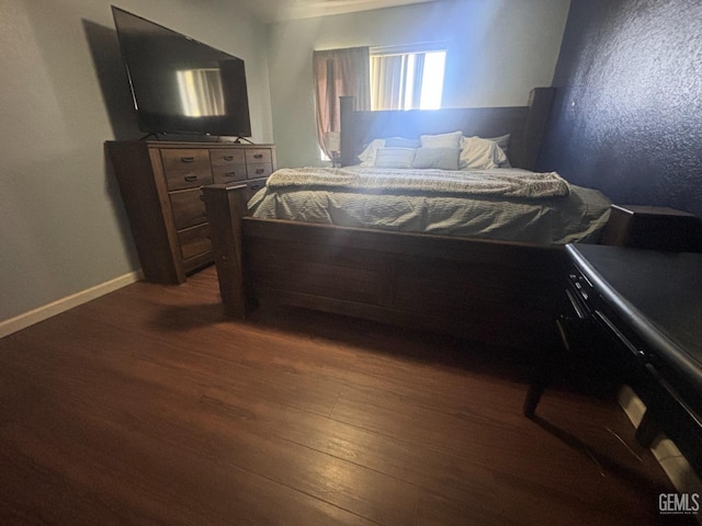 bedroom with baseboards and dark wood-type flooring