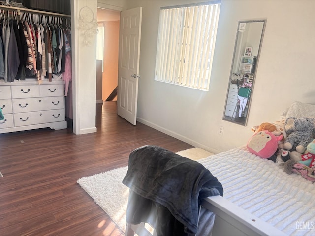 bedroom with dark wood-style floors, baseboards, and a closet