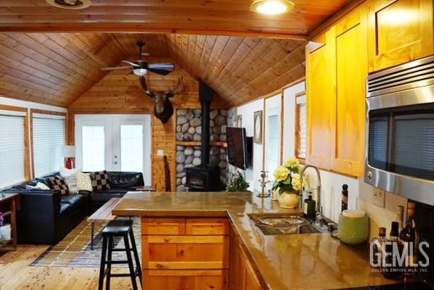 45864 Upndown Rd, Posey, CA 93260 - kitchen with stainless steel microwave, a peninsula, ceiling fan, a sink, and a wood stove