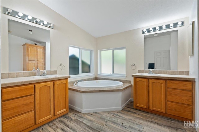 22940 Fast Ct, Bakersfield, CA 93314 - full bathroom featuring vaulted ceiling, two vanities, a garden tub, and wood finished floors