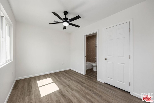 unfurnished bedroom featuring wood-type flooring, connected bathroom, and ceiling fan