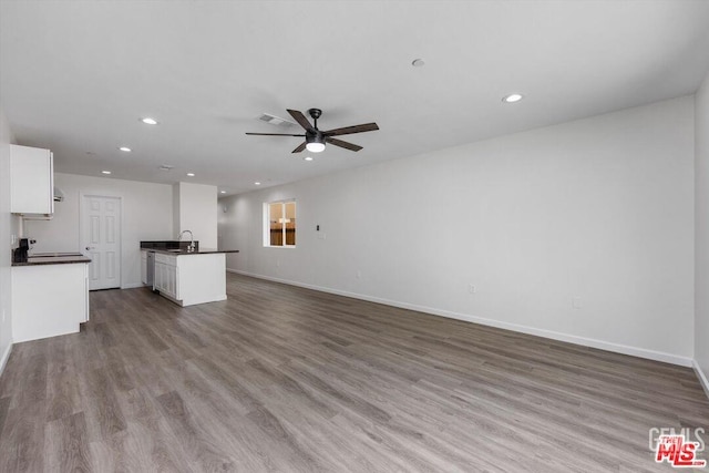 unfurnished living room featuring sink, ceiling fan, and light wood-type flooring