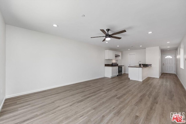 unfurnished living room featuring sink, ceiling fan, and light wood-type flooring