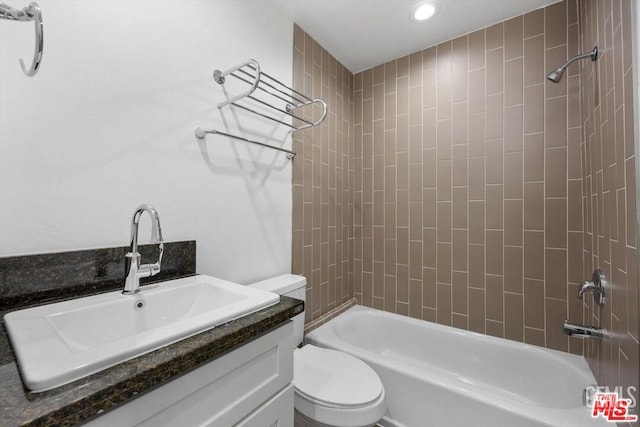 full bathroom with tiled shower / bath, vanity, and toilet