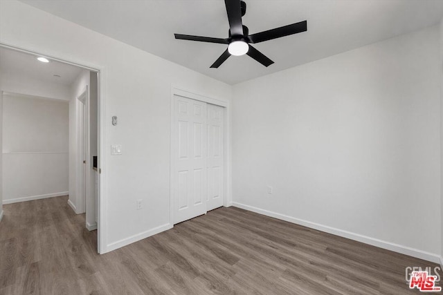 unfurnished bedroom with wood-type flooring, ceiling fan, and a closet