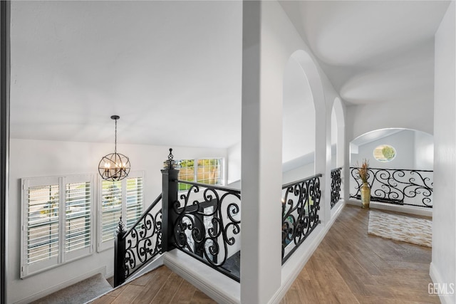 hall featuring an upstairs landing, baseboards, an inviting chandelier, and wood finished floors