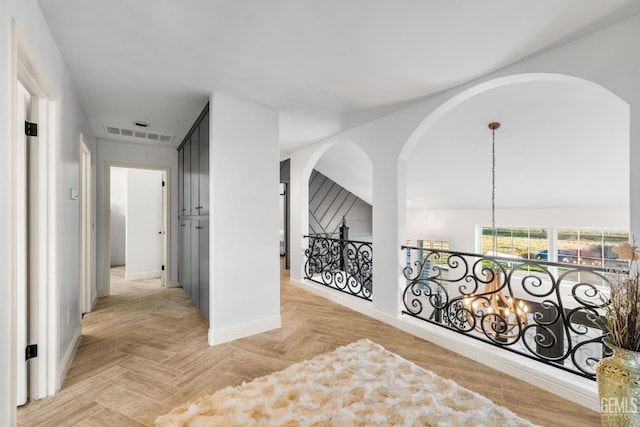 hallway featuring visible vents, baseboards, and an upstairs landing