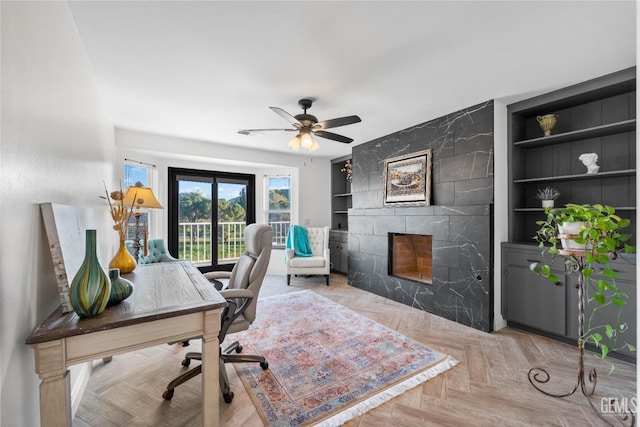 home office featuring built in features, a ceiling fan, and a high end fireplace