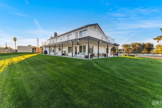 rear view of house featuring a patio, a ceiling fan, and a lawn