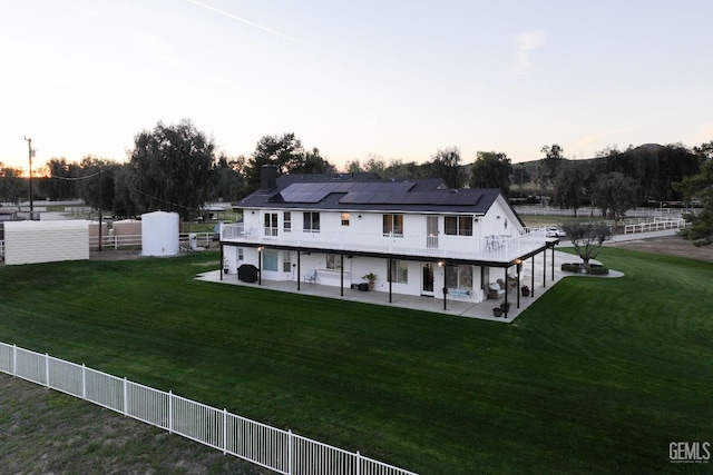 rear view of house featuring solar panels, fence private yard, a lawn, a chimney, and a patio area