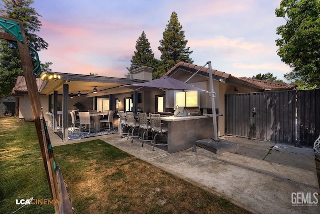 10005 Valley Forest Ct, Bakersfield, CA 93311 - back of house at dusk featuring a patio, a tiled roof, outdoor dry bar, ceiling fan, and a yard