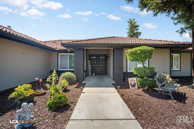 10005 Valley Forest Ct, Bakersfield, CA 93311 - doorway to property with brick siding and a tile roof
