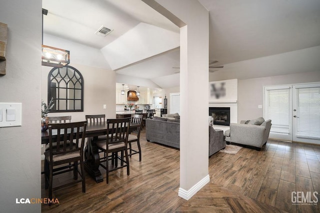 10005 Valley Forest Ct, Bakersfield, CA 93311 - dining room featuring lofted ceiling, a ceiling fan, dark wood-style flooring, visible vents, and a large fireplace