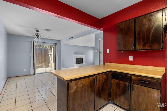 2617 Auburn Ct, Bakersfield, CA 93306 - kitchen with light tile patterned flooring, light countertops, ceiling fan, a fireplace, and a peninsula
