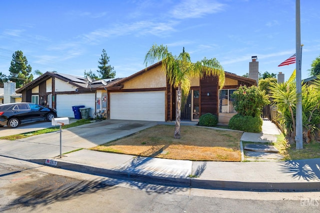 2617 Auburn Ct, Bakersfield, CA 93306 - view of front of property featuring an attached garage, roof mounted solar panels, concrete driveway, stucco siding, and a chimney