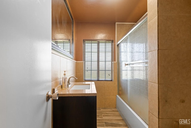 bathroom with tile walls, vanity, shower / bathtub combination, and hardwood / wood-style flooring