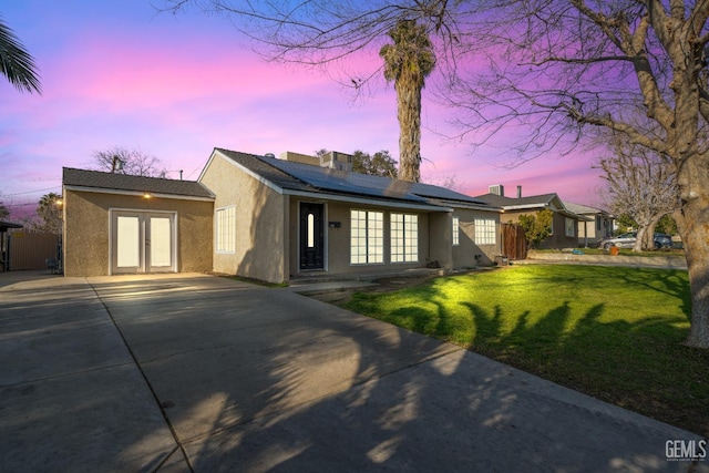 ranch-style home with a lawn, solar panels, and french doors