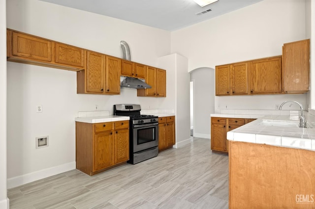 3410 Kimmie Rachelle Ct, Bakersfield, CA 93313 - kitchen featuring stainless steel gas range oven, under cabinet range hood, and brown cabinetry