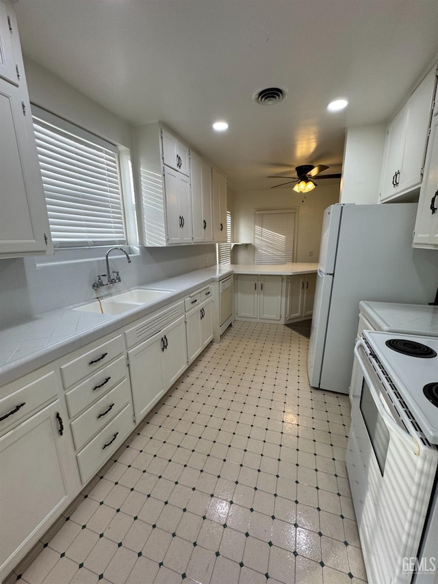 kitchen with white cabinets, white appliances, sink, and tile countertops