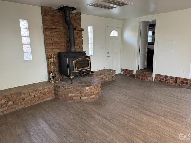 unfurnished living room featuring a wood stove, hardwood / wood-style floors, and plenty of natural light