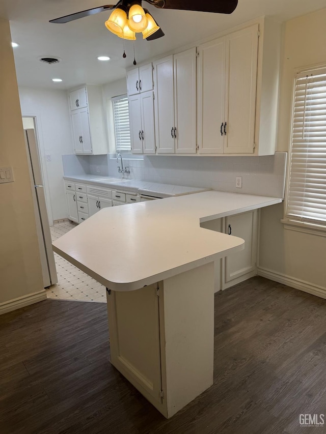 kitchen featuring white cabinetry, sink, dark hardwood / wood-style flooring, kitchen peninsula, and a breakfast bar