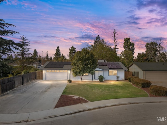ranch-style home with fence, roof mounted solar panels, a garage, concrete driveway, and a yard