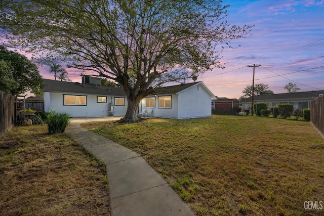 view of front of property with fence private yard, stucco siding, and a yard